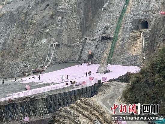 工人正給大壩穿上粉紅色“保溫被”。何浠攝 工人正給大壩穿上粉紅色“保溫被”。何浠攝