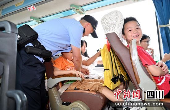 民警在逐一檢查孩子們的安全帶。四川公安供圖 民警在逐一檢查孩子們的安全帶。四川公安供圖