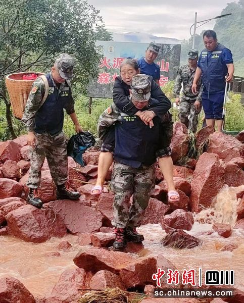 救援人員背著老人轉移并通過垮塌路段。樂山應急供圖 救援人員背著老人轉移并通過垮塌路段。樂山應急供圖