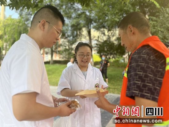 醫務人員為環衛工人送上清暑飲品。 西充縣中醫醫院供圖 醫務人員為環衛工人送上清暑飲品。 西充縣中醫醫院供圖
