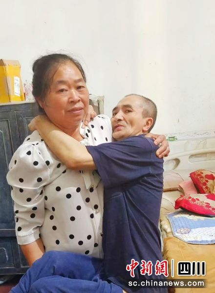 王明友抱丈夫坐輪椅。 鄧建剛 攝 王明友抱丈夫坐輪椅。 鄧建剛 攝